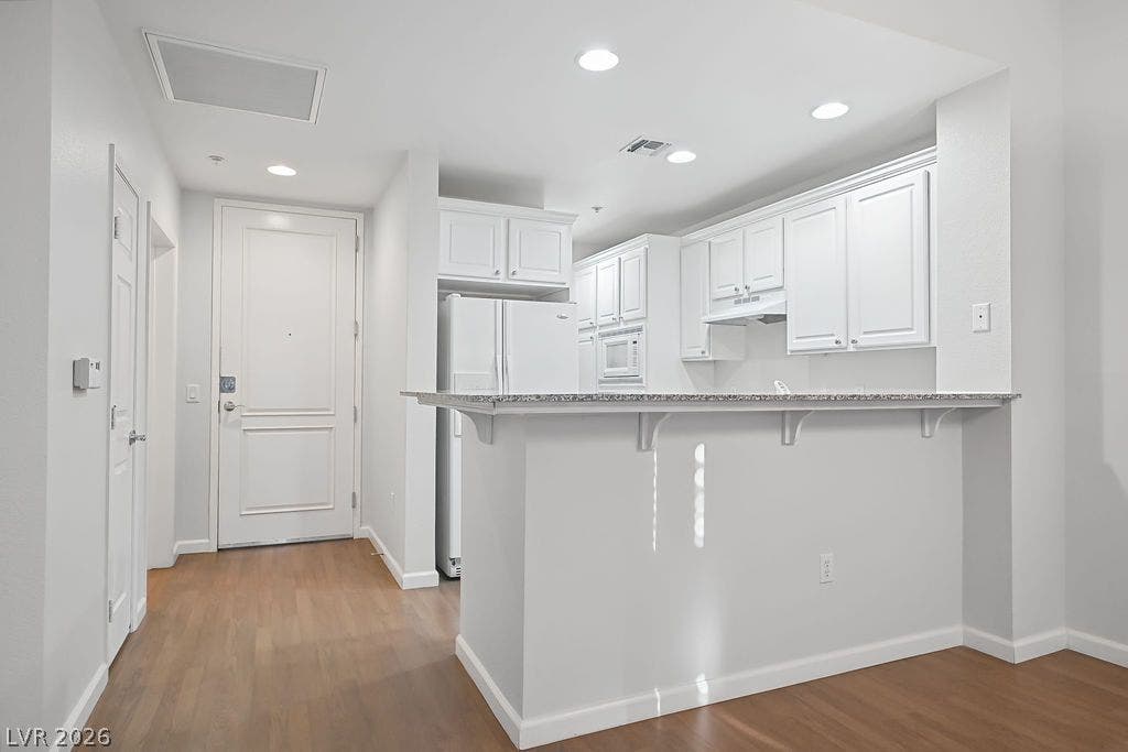 47 E Agate Avenue, #301, Las Vegas, NV 89123 Warm wood flooring contrasts beautifully with classic white cabinetry in this open kitchen entryway.