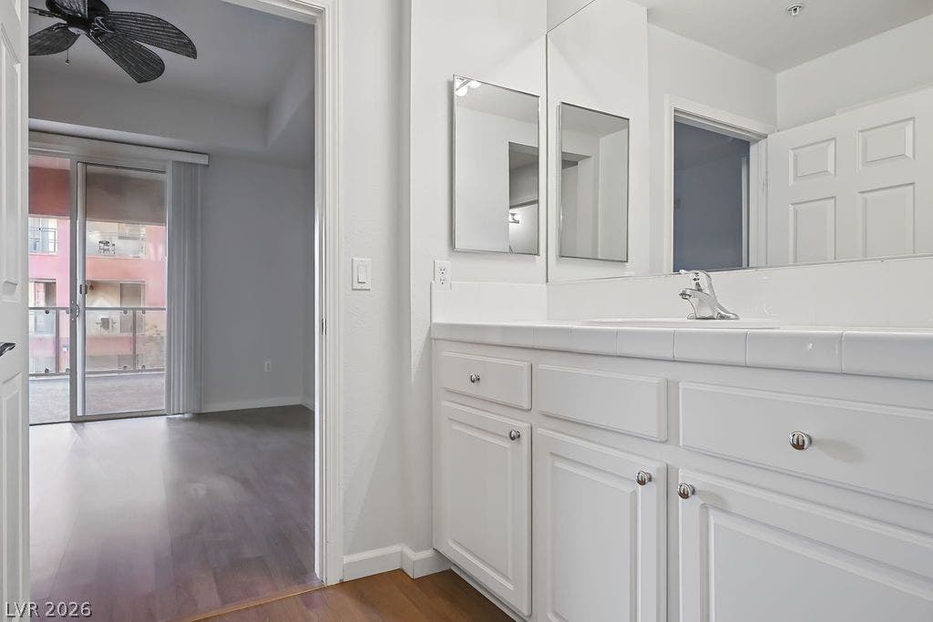 47 E Agate Avenue, #301, Las Vegas, NV 89123 Tiled countertops and crisp white cabinetry define this clean bathroom space alongside wood-finish flooring.