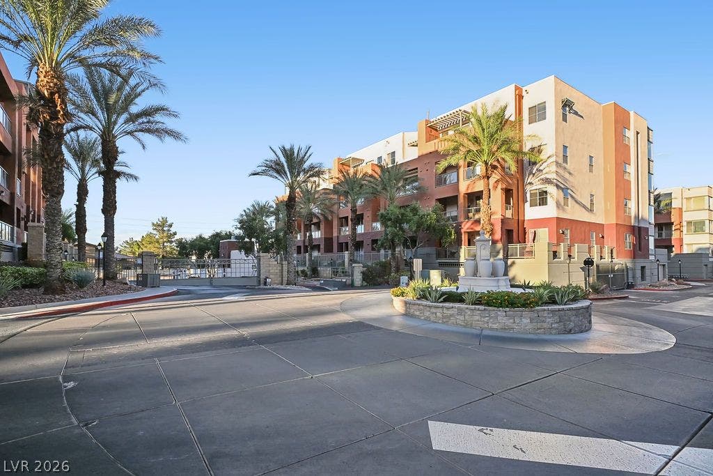 47 E Agate Avenue, #301, Las Vegas, NV 89123 An inviting gated entrance features a central roundabout with a decorative stone fountain and palm trees.