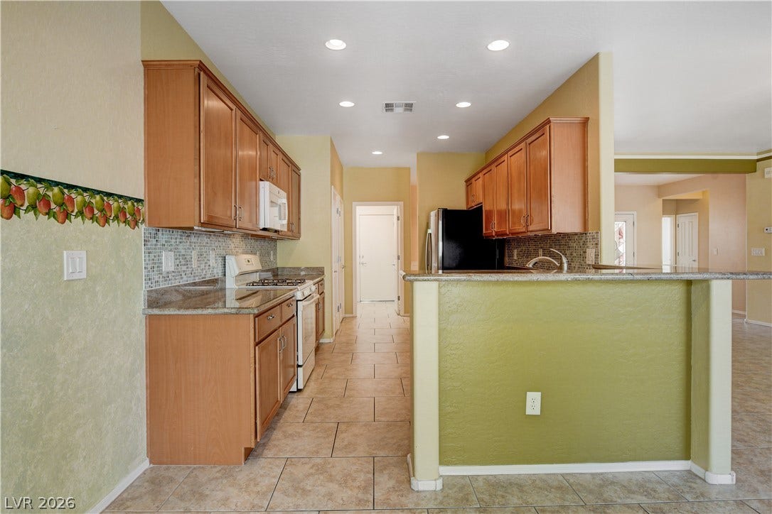 2612 Rock Pigeon Avenue, North Las Vegas, NV 89084 Tiled flooring and warm cabinetry define this functional, open kitchen layout.