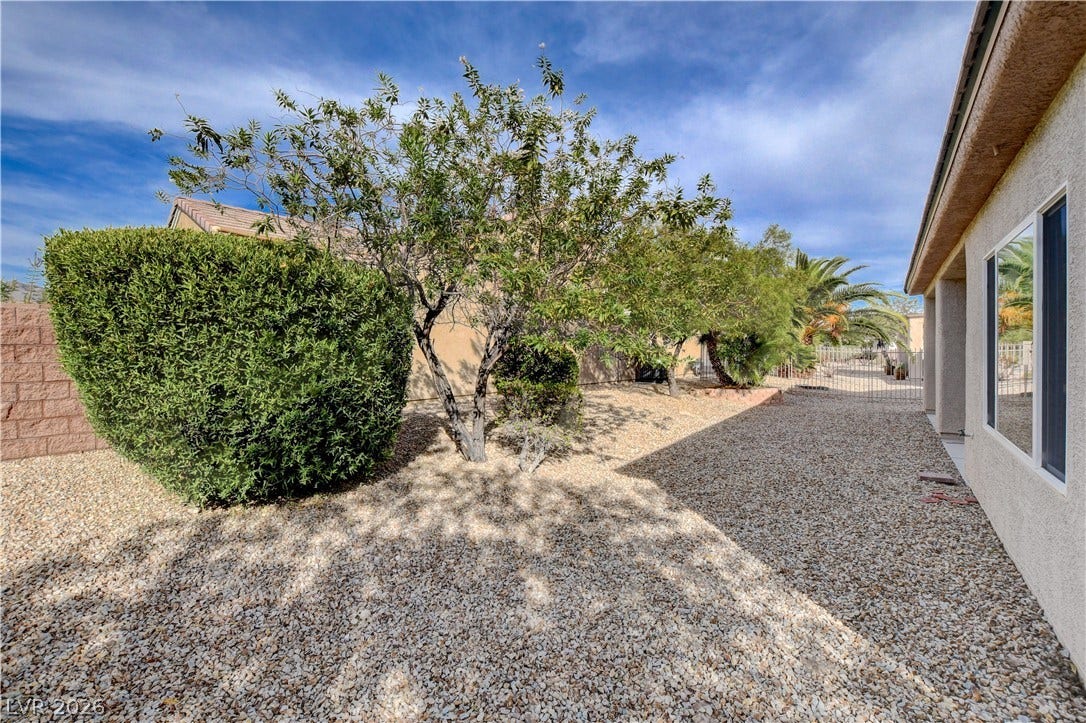 2612 Rock Pigeon Avenue, North Las Vegas, NV 89084 Low-maintenance desert landscaping and mature trees frame the side yard of this stucco home.