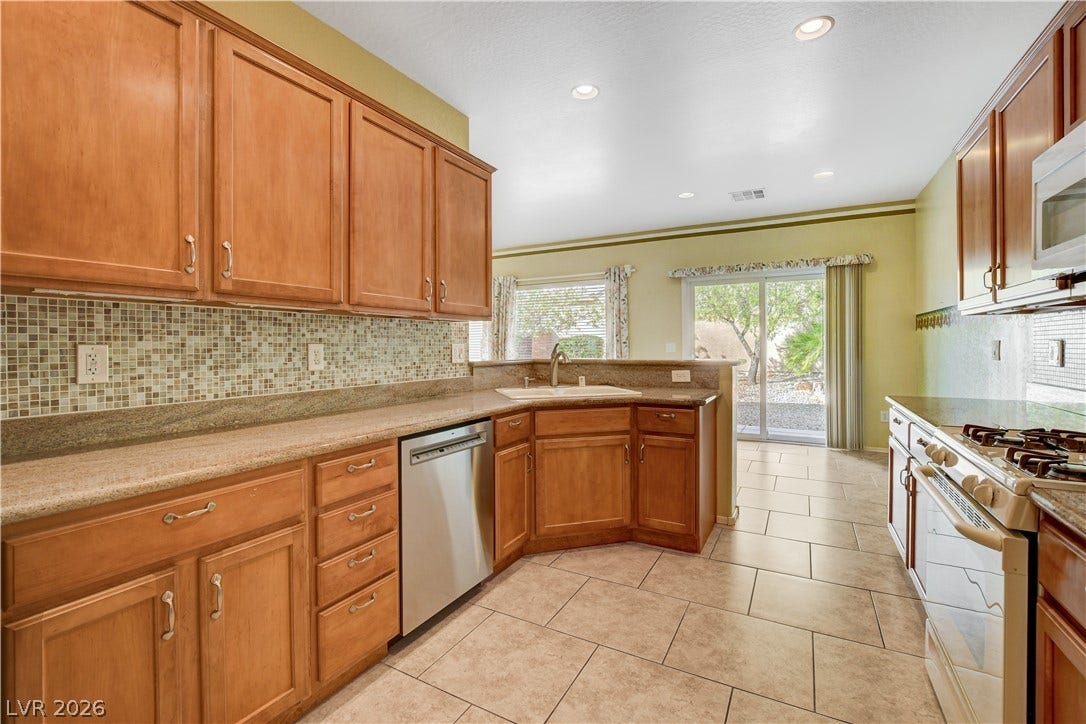 2612 Rock Pigeon Avenue, North Las Vegas, NV 89084 Warm wood cabinetry and tile flooring define this functional workspace seamlessly open to the dining area.