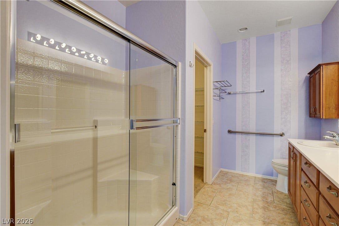 2612 Rock Pigeon Avenue, North Las Vegas, NV 89084 A spacious walk-in shower with sliding glass doors sits adjacent to a vanity with wood cabinetry.