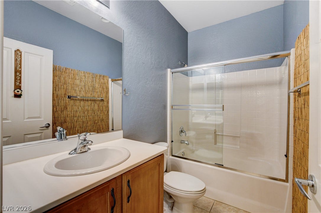 2612 Rock Pigeon Avenue, North Las Vegas, NV 89084 An inviting bathroom features a classic tub-shower combination alongside a warm wood vanity.