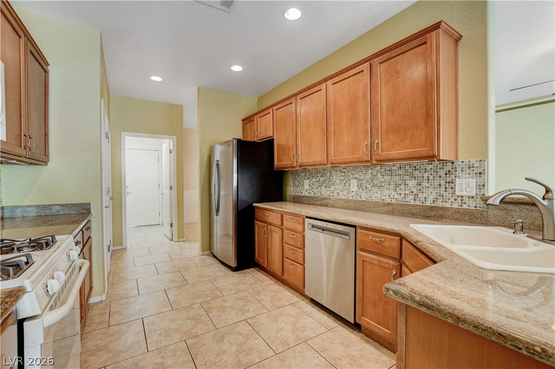 2612 Rock Pigeon Avenue, North Las Vegas, NV 89084 Warm wood cabinetry and tile flooring define this functional galley kitchen layout.