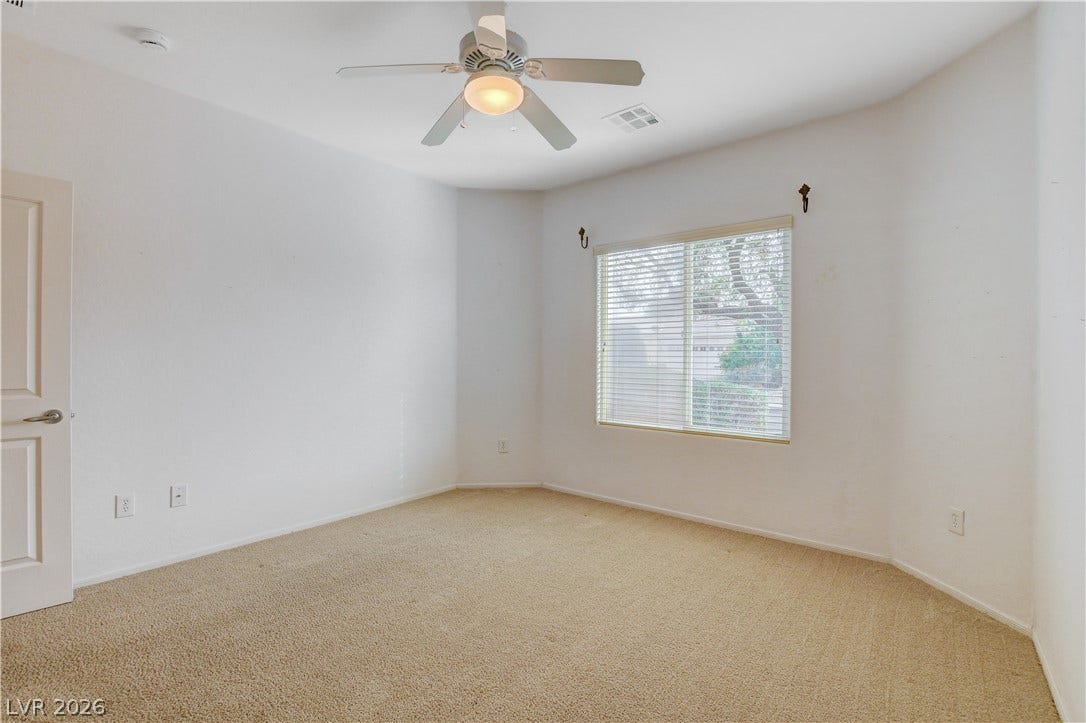 2612 Rock Pigeon Avenue, North Las Vegas, NV 89084 Plush carpeting and a large window facing mature trees define this comfortable bedroom.