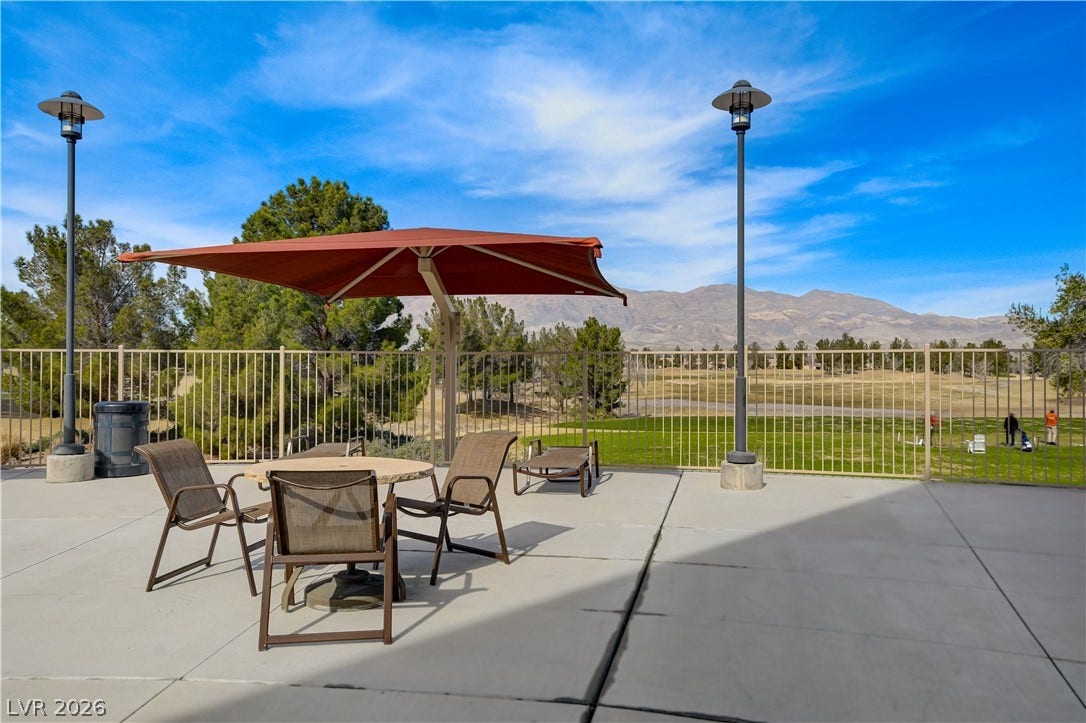 2612 Rock Pigeon Avenue, North Las Vegas, NV 89084 An open concrete patio overlooks a lush green golf course and distant mountain peaks.