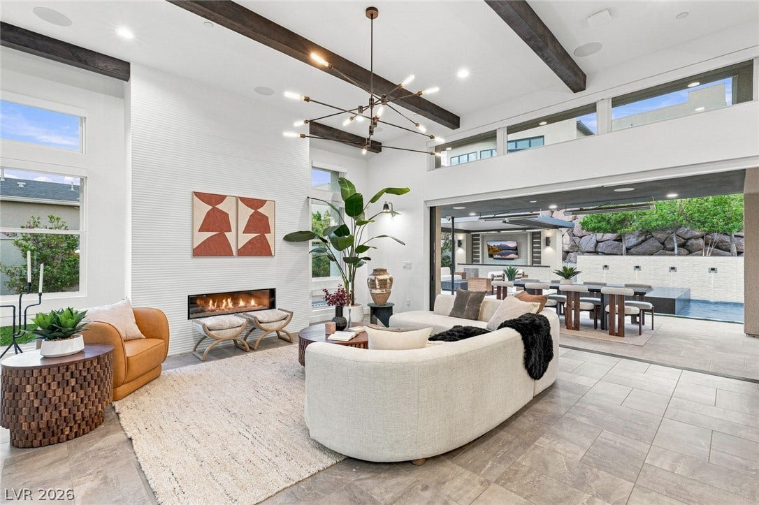 Exposed ceiling beams and a modern linear fireplace anchor this seamless indoor-outdoor living space.