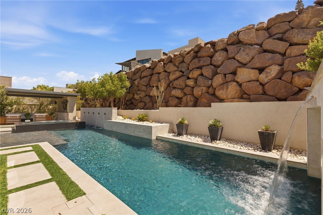 An inviting swimming pool borders a dramatic stone retaining wall in this private backyard oasis.