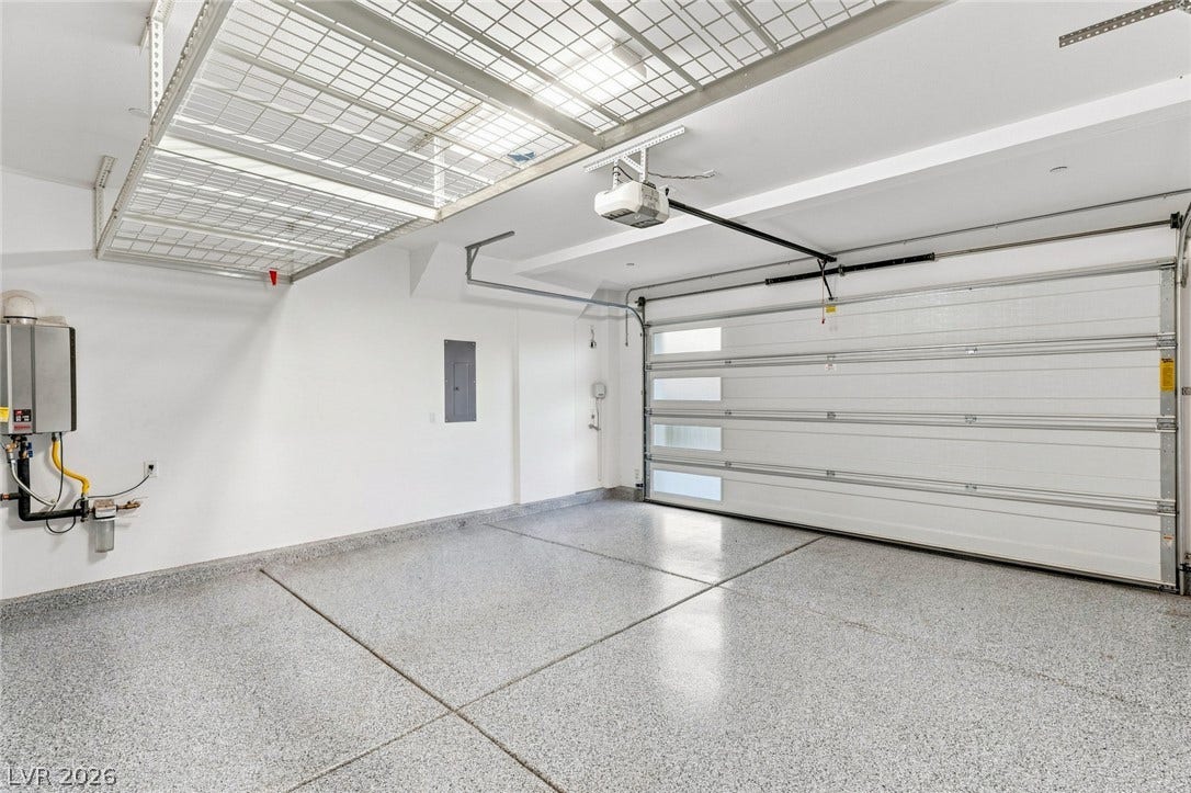 Polished epoxy floors and integrated overhead storage shelves define this clean, modern garage space.