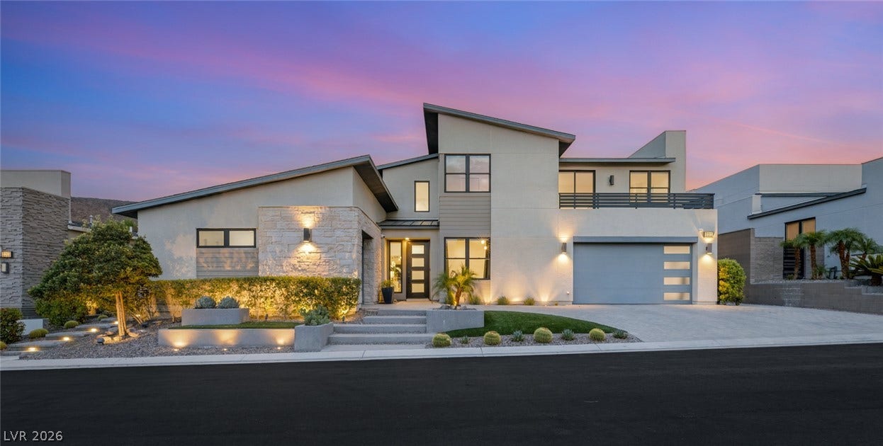 Dramatic rooflines and stone accents define this contemporary two-story exterior at twilight.