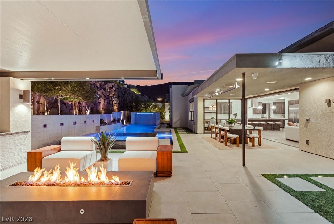 An expansive modern terrace seamlessly transitions to a luxurious pool deck under dramatic desert skies.