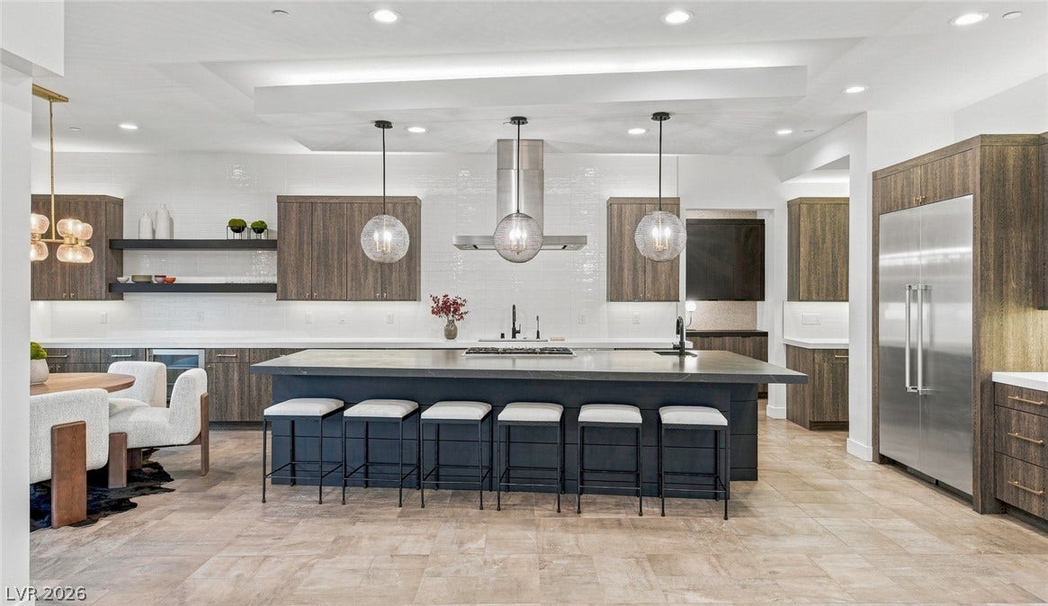 An expansive central island and warm wood cabinetry anchor this modern culinary workspace.