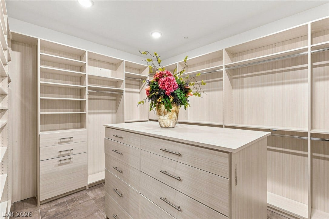 Custom built-in shelving and a spacious center island maximize storage in this walk-in closet.