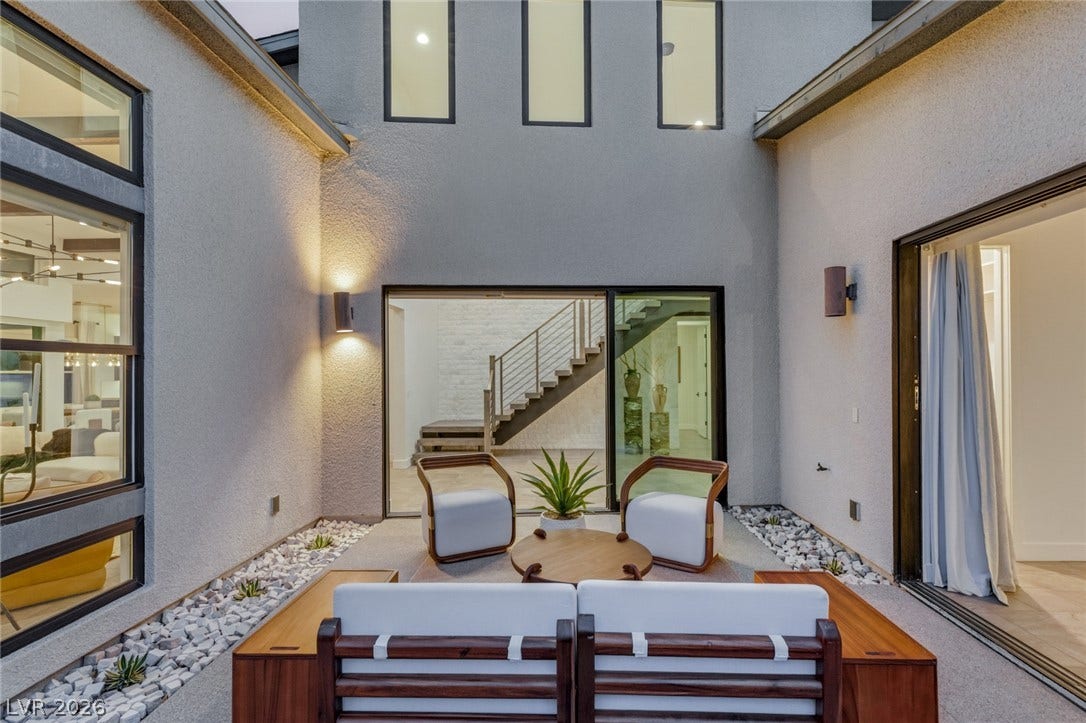An intimate central courtyard displays textured stucco walls and large glass doors.