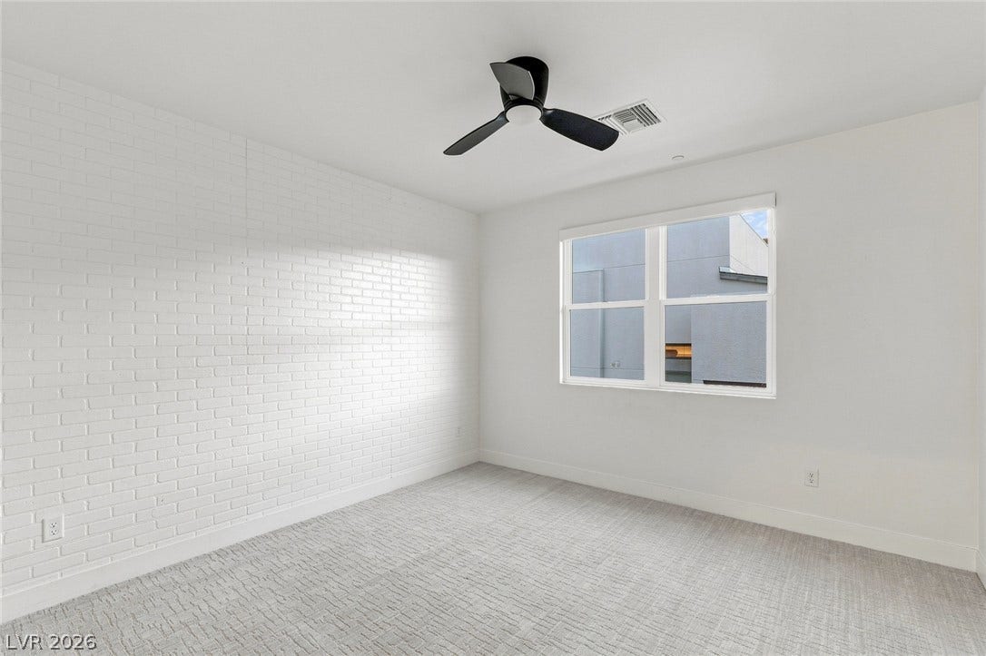 Textured carpet pairs with a light-filled window and an elegant masonry wall.