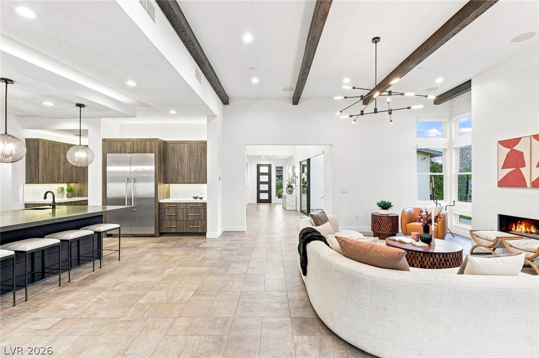 Exposed wood beams and a modern fireplace elevate this grand open-concept living space.