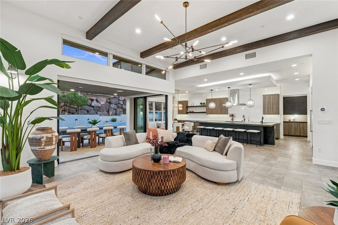 Exposed wood beams and modern tile flooring define this spacious open living area.