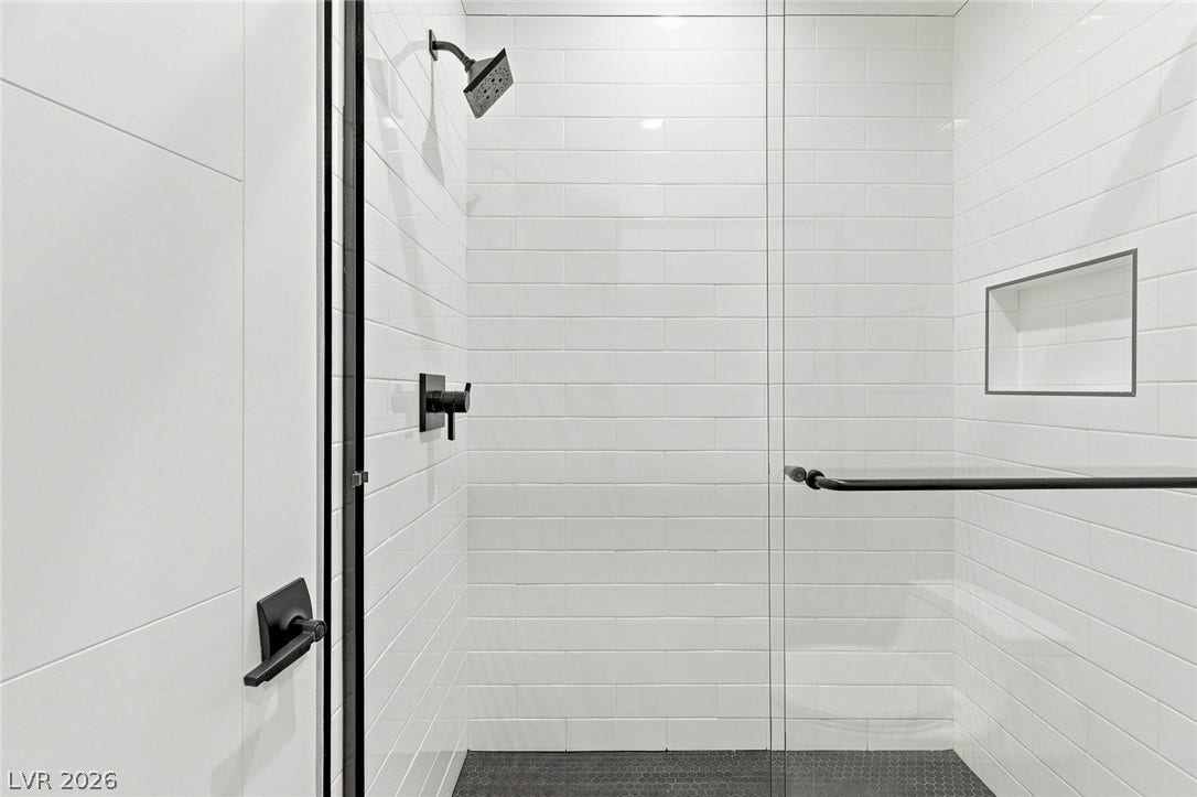 Clean subway tile lines this walk-in shower behind a seamless glass door.