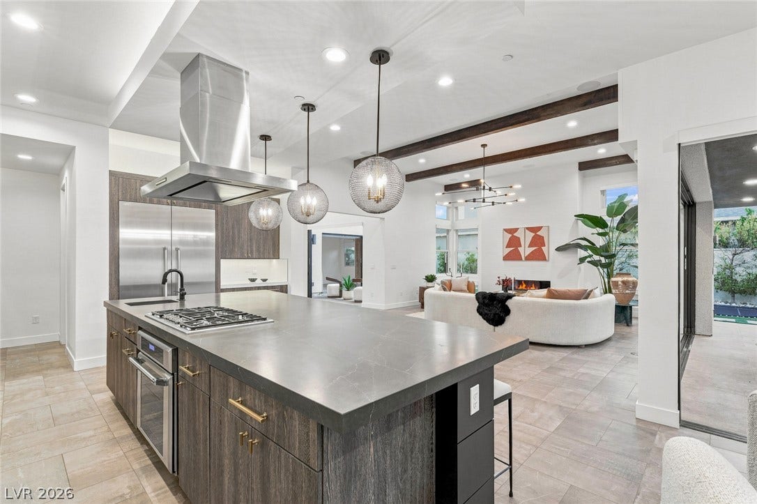 A spacious kitchen flows seamlessly into an open-concept living area with elegant ceiling details.
