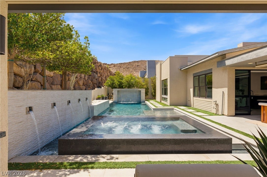 An inviting backyard oasis features a modern pool with integrated spa and soothing water features.