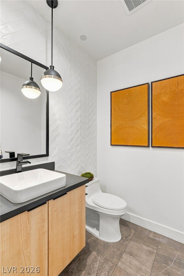 Chevron wall tile and stone-look flooring establish a contemporary aesthetic in this powder room.