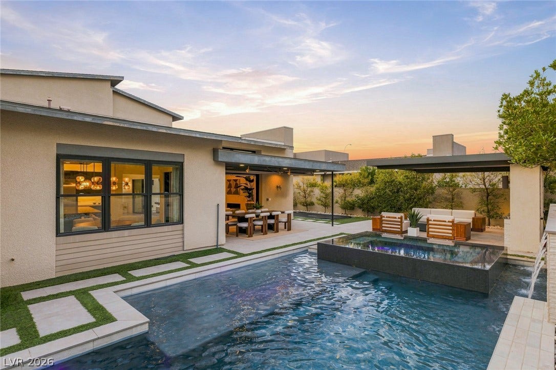 An inviting backyard oasis features a modern swimming pool paired with a raised integrated spa.