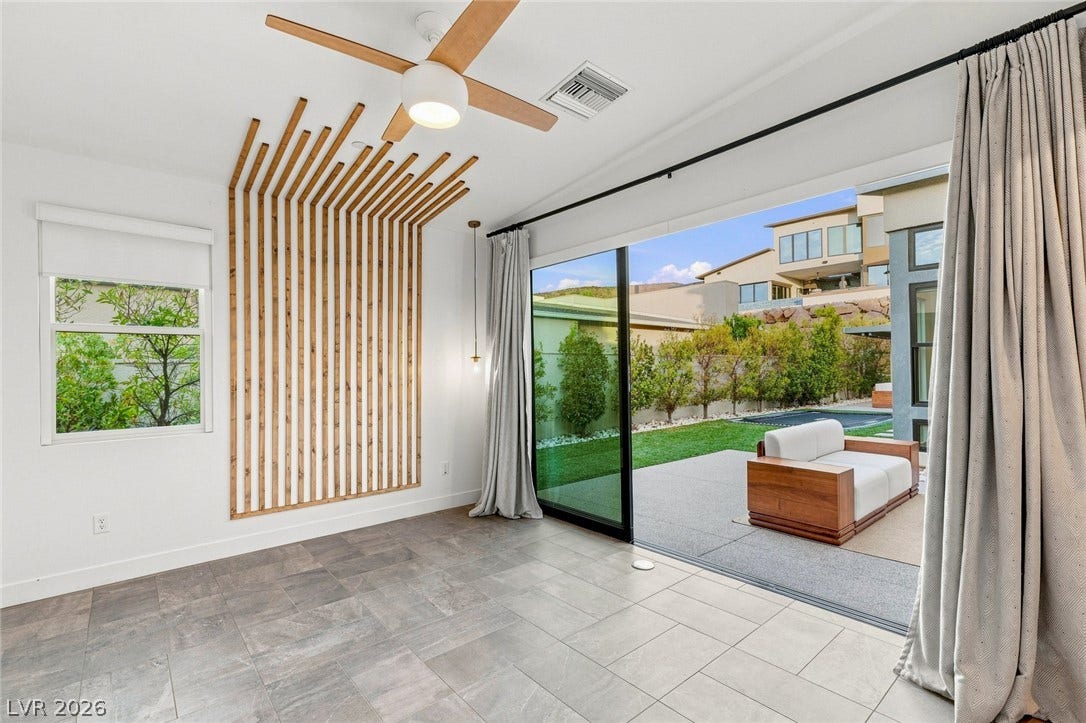 Massive sliding glass doors merge sleek tile flooring with a private backyard terrace.