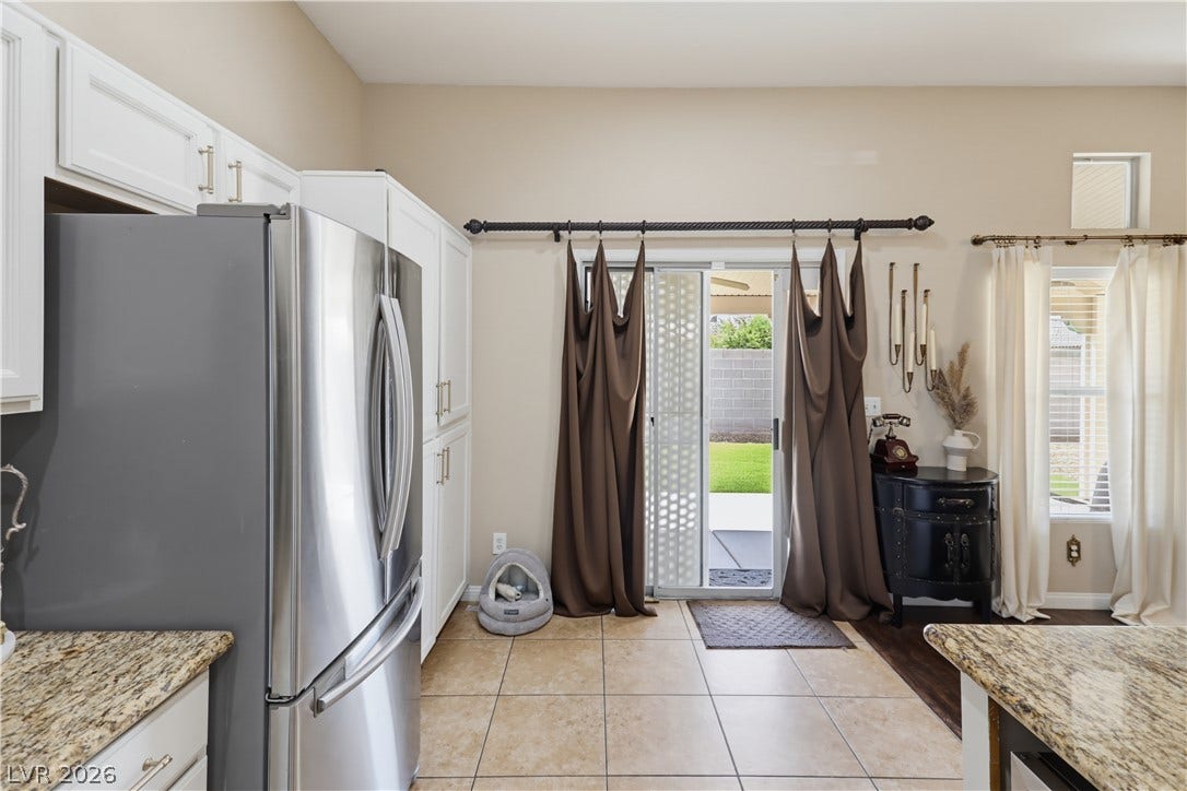 3211 Panamint Court, North Las Vegas, NV 89032 Granite countertops and clean tile floors frame a bright kitchen with sliding door backyard access.