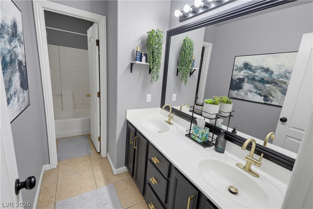 3211 Panamint Court, North Las Vegas, NV 89032 A classic tiled floor bathroom includes dual sinks alongside gold-toned plumbing fixtures.