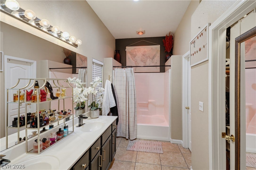 3211 Panamint Court, North Las Vegas, NV 89032 A spacious bathroom displays dual vanities, neutral tiling, and a classic shower tub combination.
