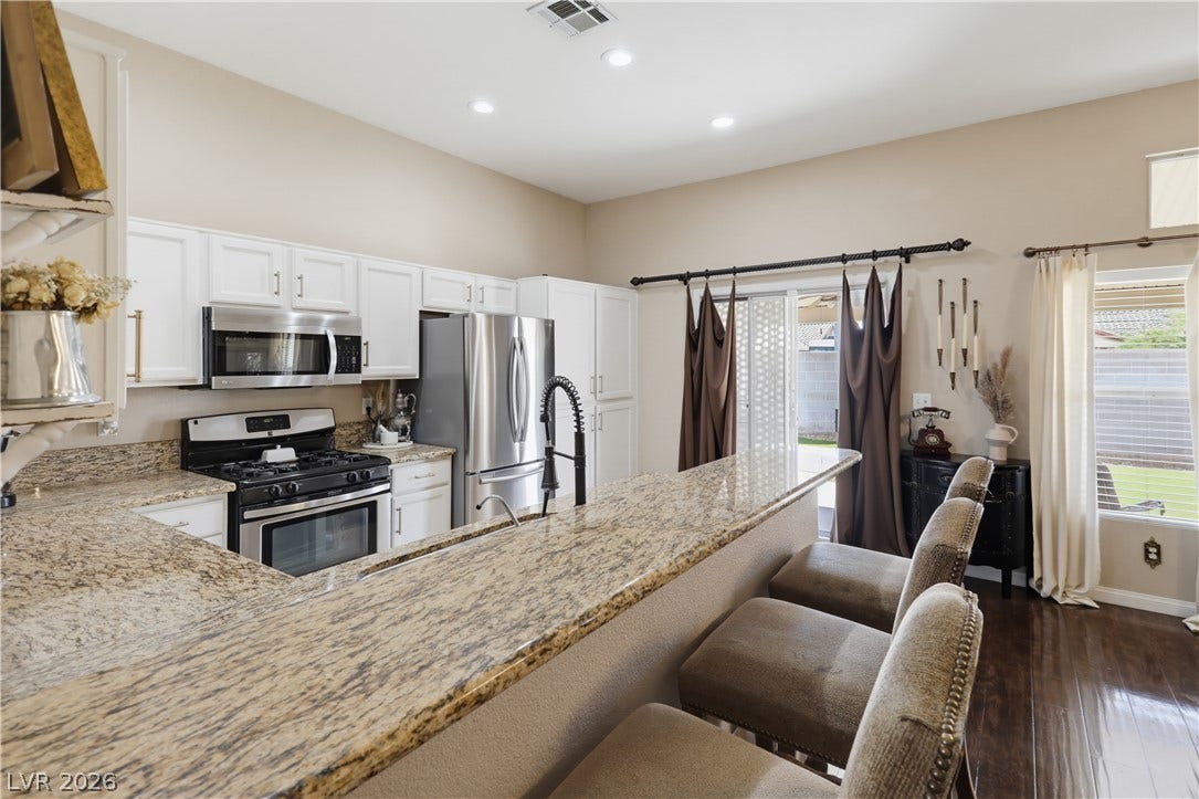 3211 Panamint Court, North Las Vegas, NV 89032 Rich granite countertops pair with classic cabinetry and polished hardwood floors in this refined kitchen.