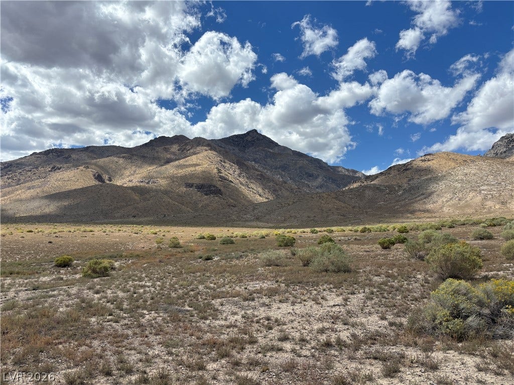 WP Co. WP Co. Road 31 (N. Spring Valley Rd), Ely, NV 89301 Dramatic mountain peaks rise high above the natural desert landscape under a cloudy blue sky.