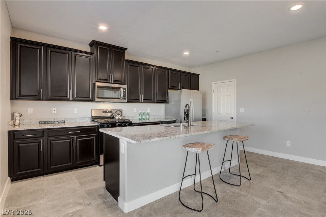 Rich dark cabinetry and polished stone countertops elevate this modern cooking space.