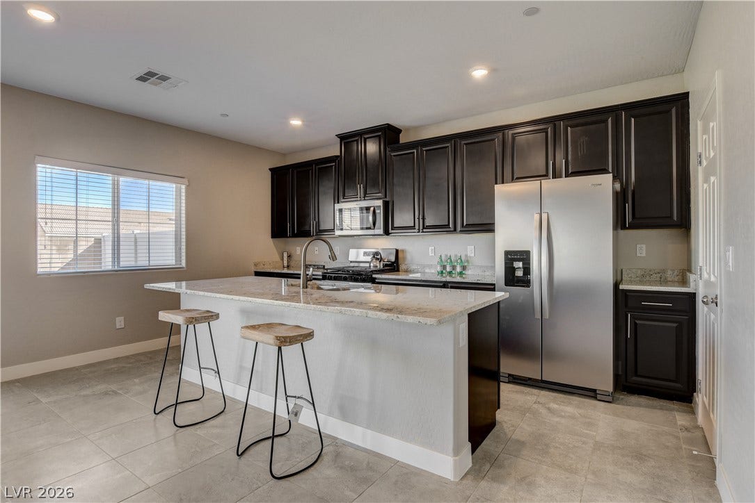 Dark cabinetry and gleaming stone countertops create a refined culinary workspace.
