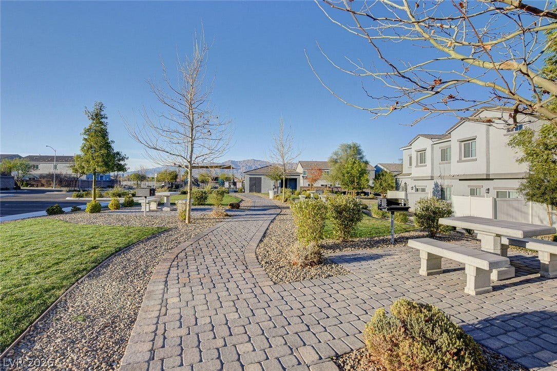 A winding paver pathway guides visitors through landscaped common areas under open blue skies.