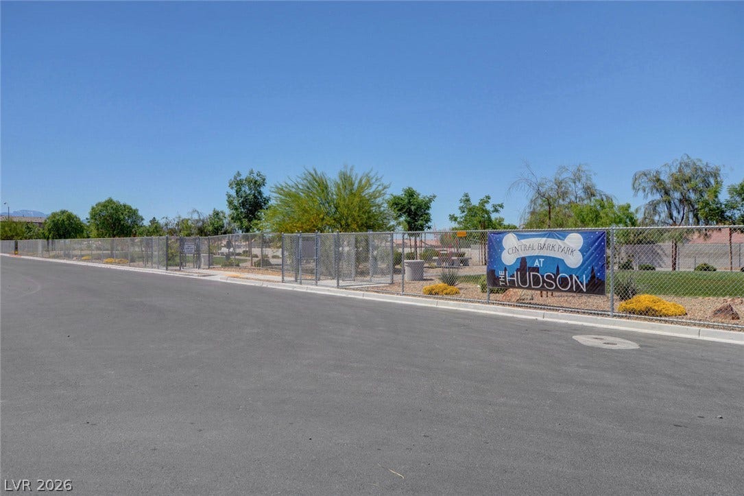 A fenced community dog park is conveniently situated adjacent to the paved street.