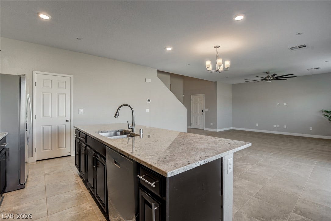 An open floorplan seamlessly connects the stone-countertop kitchen island to the main living area.
