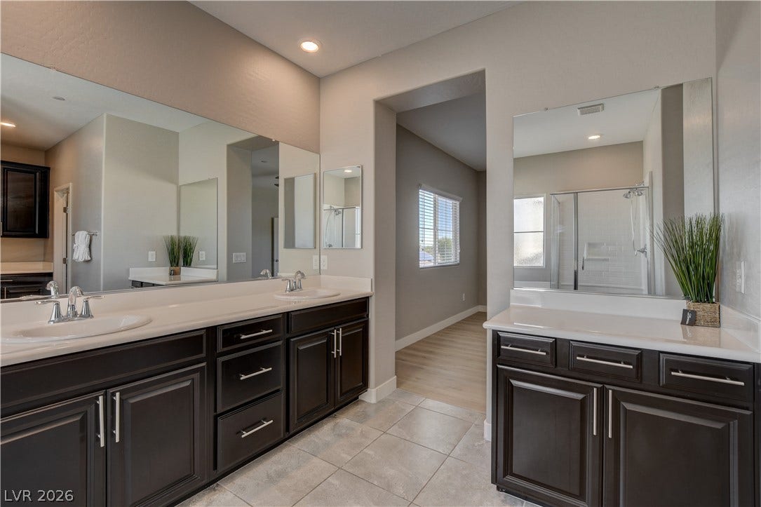 Gleaming tile floors and dark cabinetry define this spacious, modern bathroom layout.