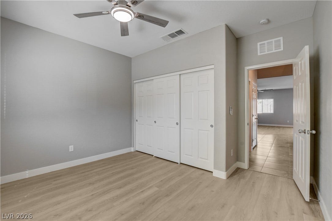 Smooth wood-style flooring runs throughout this versatile room featuring clean walls and ample closet storage.
