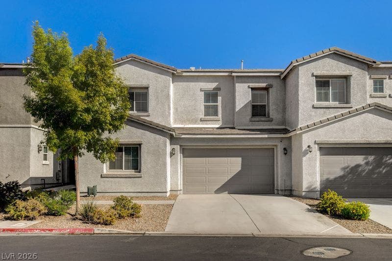 A classic stucco exterior frames the front entryway and garage of this multi-level townhome.