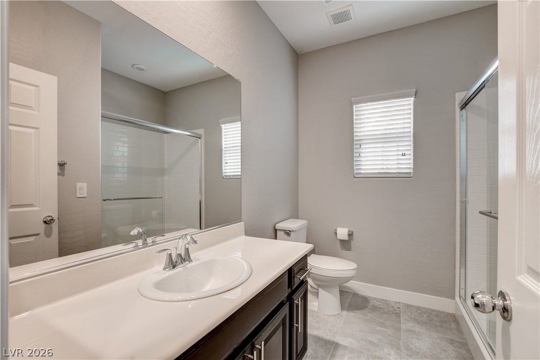 A glass-enclosed shower and tile flooring anchor this functional bathroom space.