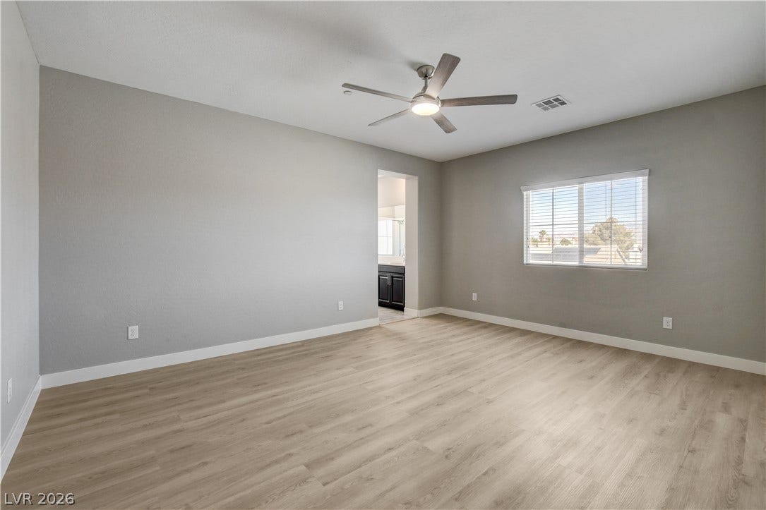 A spacious bedroom features modern wood-style flooring and direct access to an en suite bath.
