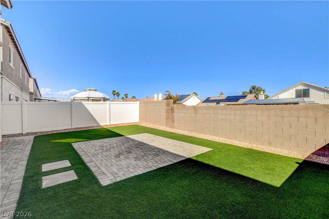 A neat patio of interlocking pavers transitions to manicured green turf under wide open skies.
