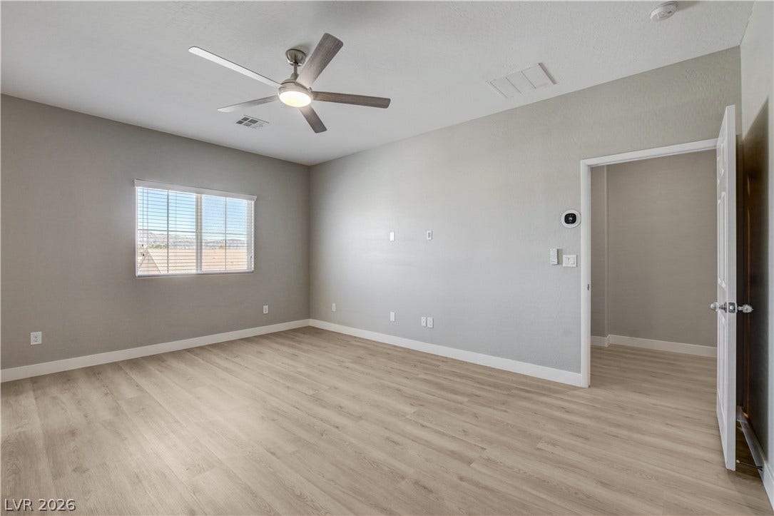 Smooth wood-style flooring and high ceilings define this versatile, light-filled bedroom space.