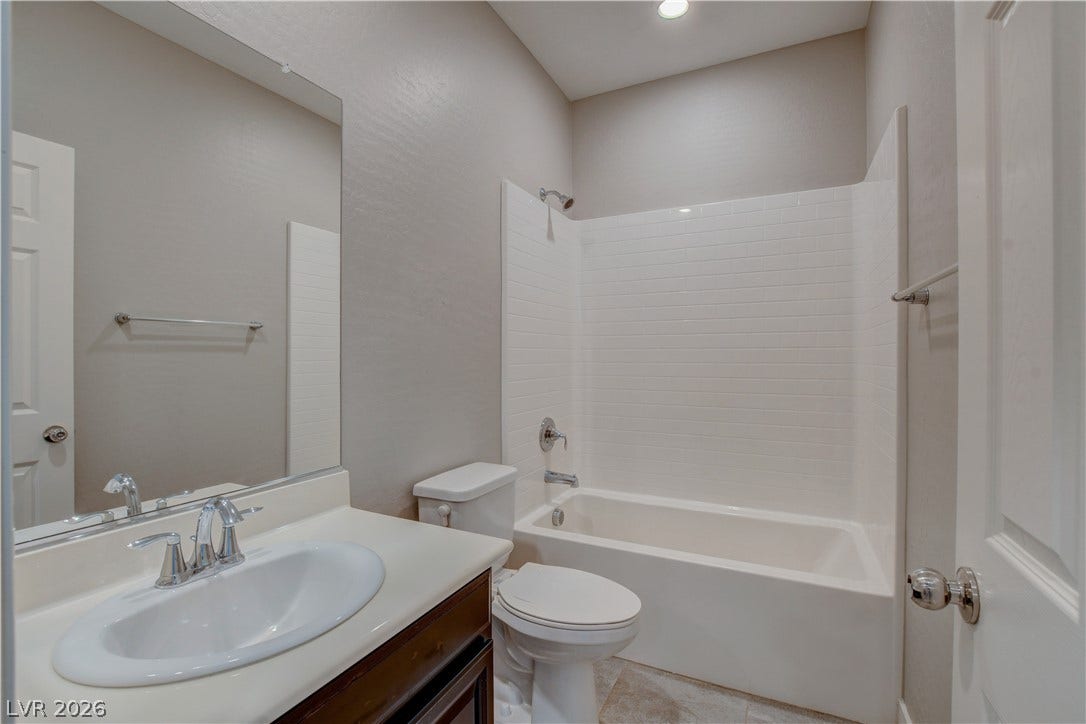 An inviting bathroom features a classic tub shower combination and neutral tile flooring.