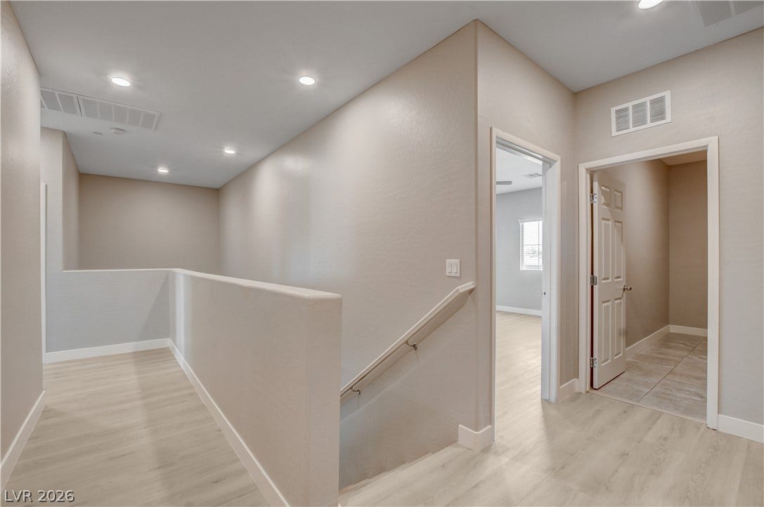 Smooth wood-look flooring and clean architectural lines define this upper-level landing.