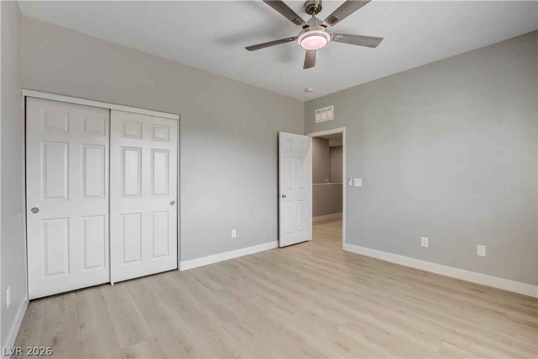 Smooth wood-style flooring runs throughout this versatile room under a high ceiling.