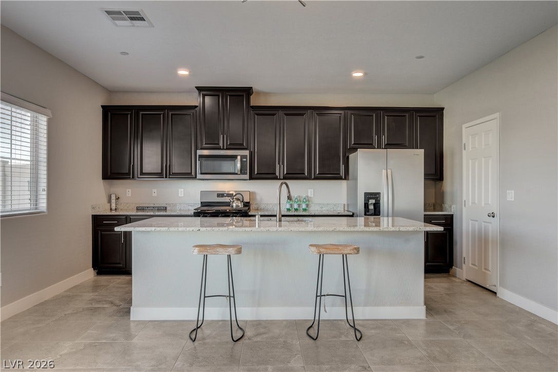 Polished tile flooring complements dark wood cabinetry and a central stone island.