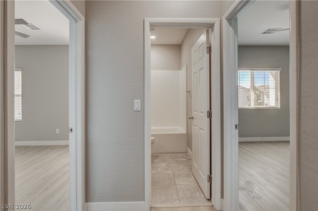 Clean lines and neutral tones define this central hallway connecting bedrooms and a bathroom.